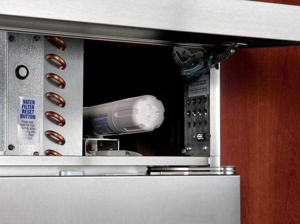 Close-up view of Sub-Zero refrigerator compartment showing a cylindrical 4204490 water filter and a Water Filter Reset Button label, with metal coils and control components visible inside.